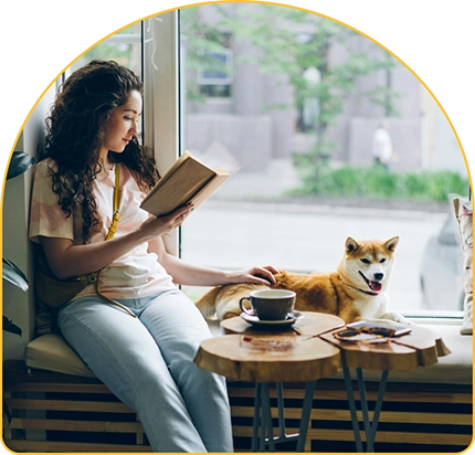 Woman reading book while petting her dog.